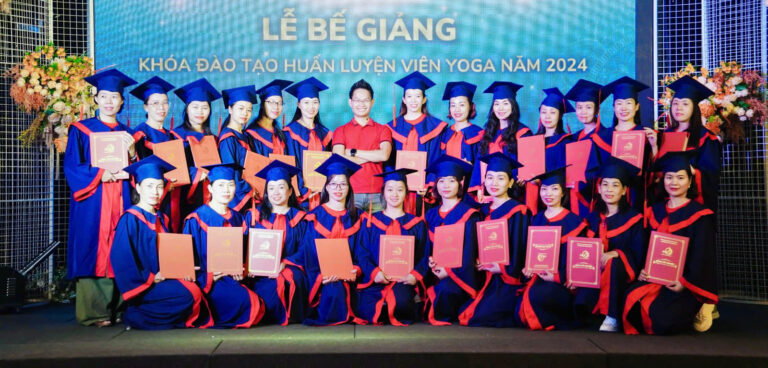 Lễ bế giảng khoá đào tạo Huấn luyện viên Yoga năm 2024, hơn hai mươi học viên mặc lễ phục tốt nghiệp cầm bằng chụp ảnh cùng Đặng Kim Ba